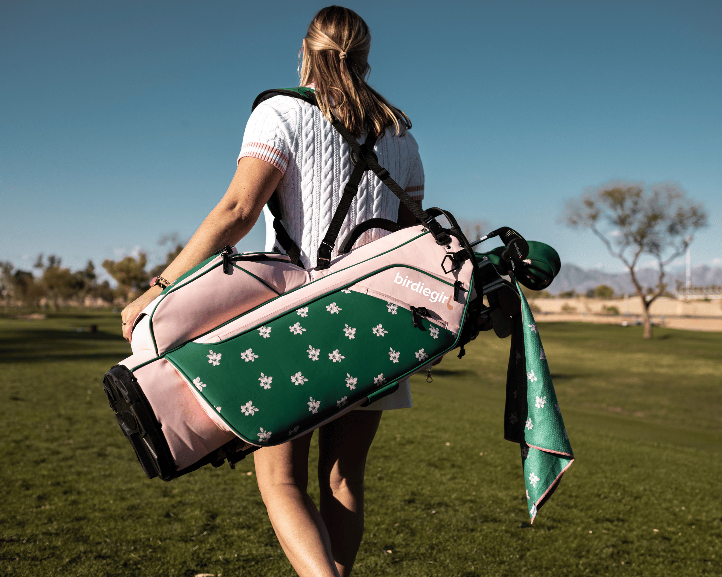 Women carrying a pink and green azalea golf bag on a golf course