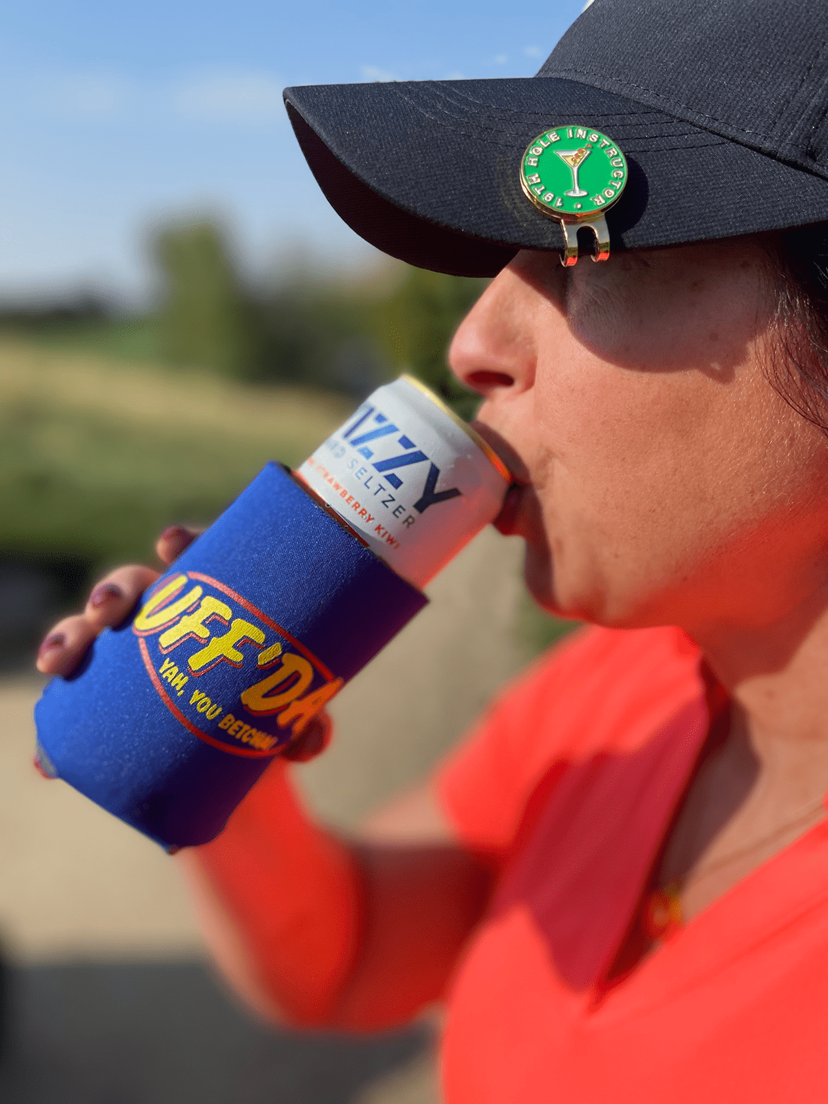 Woman Golfer with 19th hole instructor ball marker on magnetic cap clip drinking a seltzer