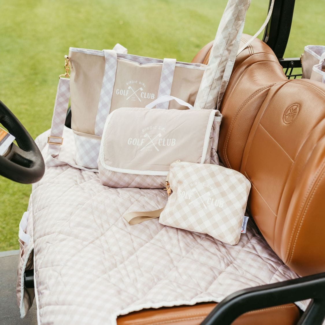 Golf cart seat cover and golf bags and accessories on a golf cart with grass in the background